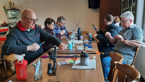 Teilnehmer beim Befiedern der Pfeile